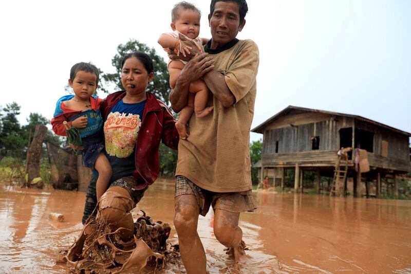 Parents carry their children as they leave their home during the flood after the Xepian-Xe Nam Noy hydropower dam collapsed in Attapeu province, Laos July 26, 2018. REUTERS/Soe Zeya Tun      TPX IMAGES OF THE DAY