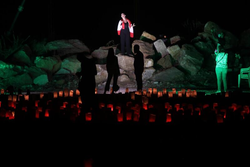 A woman sings on a pile of rubble near paper lanterns arranged in the shape of a Lebanese flag to mark one month since the city's deadly explosion. Getty Images