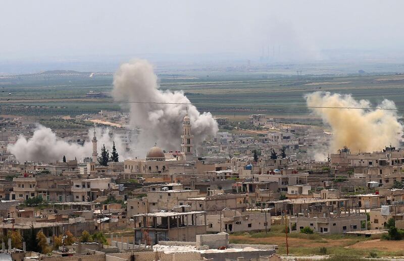 Smoke rises above buildings during shelling by Syrian regime forces and their allies on the town of Khan Sheikhun in the southern countryside of the rebel-held Idlib province on May 11, 2019.  UN-linked aid groups said they have suspended activities in parts of violence-plagued northwest Syria, where stepped up bombardment by the regime and Russia is jeopardising the safety of humanitarian workers.  / AFP / Anas AL-DYAB
