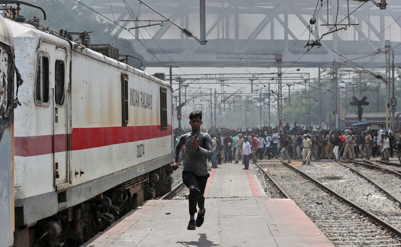 A protester flees after hearing gunshots at Secunderabad railroad station in Hyderabad, India. Thousands of youths  burned train coaches and blocked tracks and roads with boulders as demonstrations continued for a second straight day against a new government recruitment plan for the military. AP