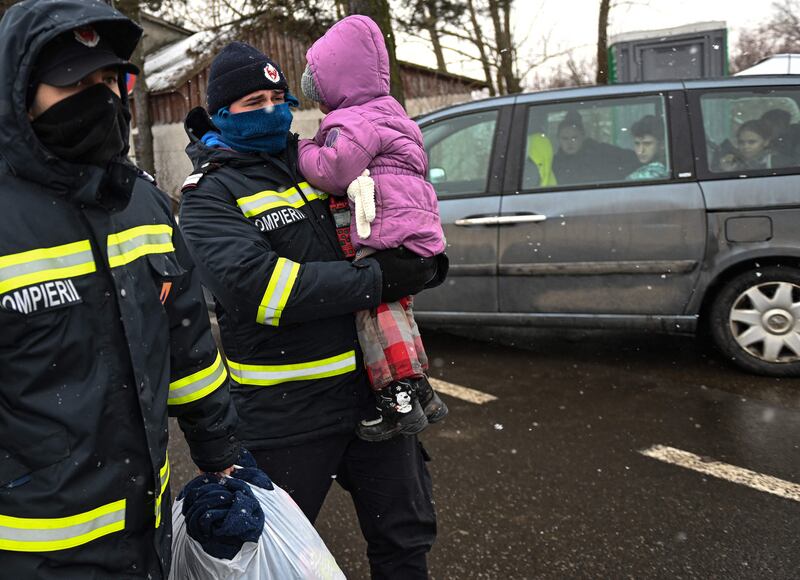 A Romanian fireman carries a refugee's child at the Ukrainian-Romanian border in Siret. AFP
