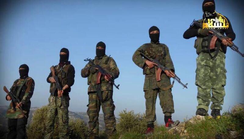 In this undated photo, released by the Turkistan Islamic Party, fighters from the group hold their weapons at an unknown place in Syria. Turkistan Islamic Party via AP