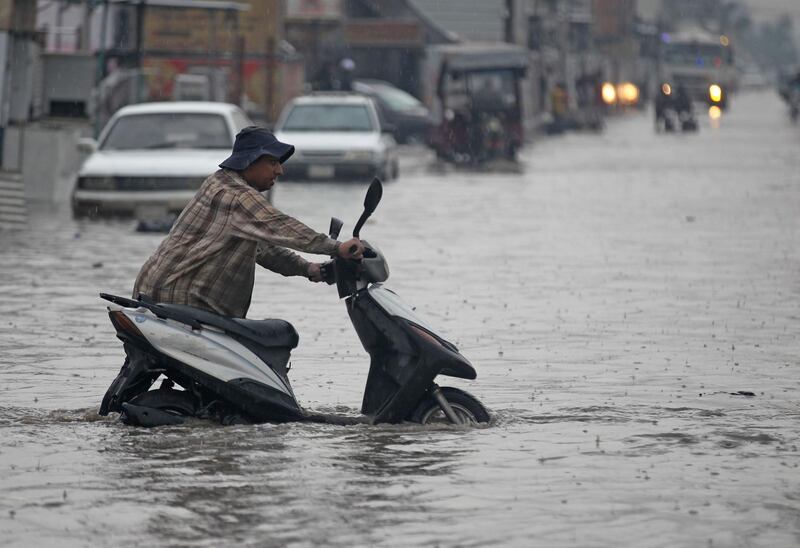 A man pushes his motorcycle through a flooded street caused by rainfall in Sadr City, east of the Iraqi capital Baghdad. AFP