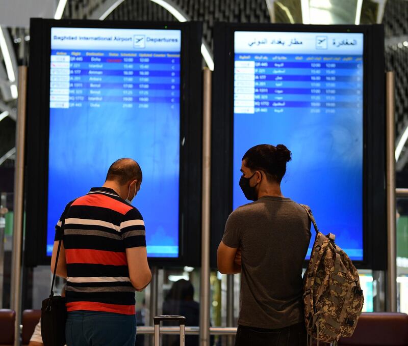 Passengers, wearing face masks waiting checking flights display screen in Baghdad International Airport on its reopening day in Baghdad, Iraq.  EPA