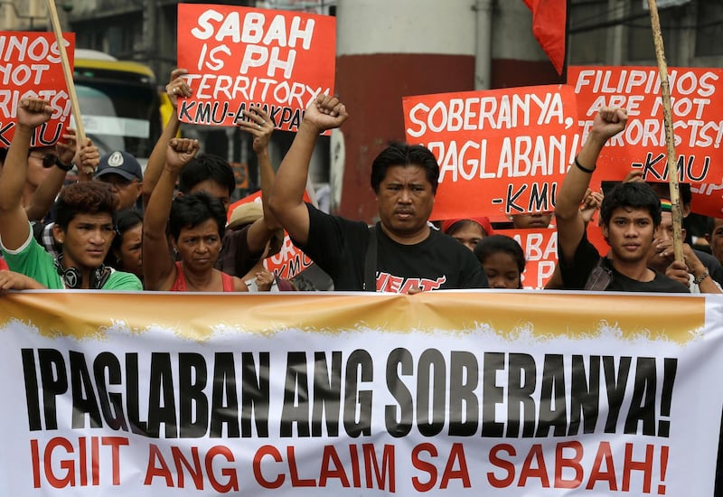 Protesters clench their fists during a rally near the Presidential Palace in Manila, Philippines Friday March 15, 2013. The protesters accused Philippine President Benigno Aquino III of "condoning" the crackdown of Filipinos living in Sabah state in Malaysia following the intrusion in a village of Lahad Datu by more than 200 "Royal Army" followers of Sultan Jamalul Kiram III to stake its claim of the disputed territory. The intrusion has led to the death of at least seven Malaysian forces and more than a dozen "Royal Army" followers. The banner reads: Fight for Sovereignty! Stake The Claim of Sabah! (AP Photo/Bullit Marquez)