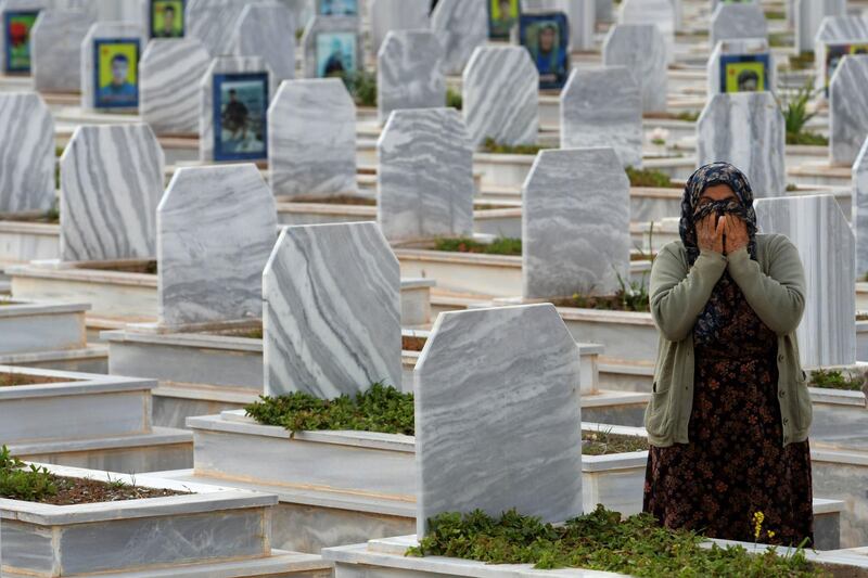 Relatives visit the tombs of Syrian Democratic Forces fighters at a cemetery in the northern Syrian-Kurdish town of Kobane, AFP