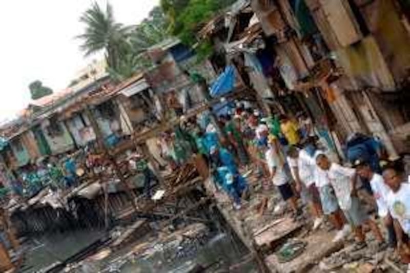 Workers from the Metropolitan Manila Development Authority (MMDA) demolish shanty structures along an open canal in Manila, 29 August 2007.  The MMDA cleared illegal structures housing thousands of squatters living along riverbanks in Manila's 17 waterways, where houses on stilts sit along the waterways, with garbage causing blockage of the canals and perennial flooding.  AFP PHOTO/Jay DIRECTO