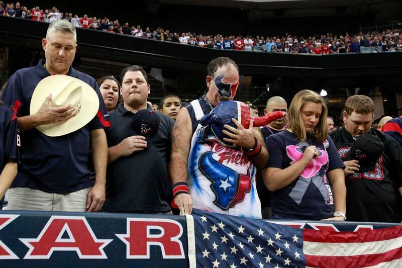 Houston Texans fans take off their hats to observe a moment of silence in memory of the Newtown shooting victims before their NFL football game against the Indianapolis Colts in Houston December 16, 2012. REUTERS/Richard Carson (UNITED STATES - Tags: SPORT FOOTBALL)
