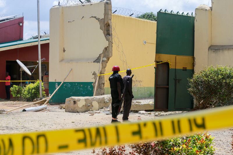 Prison officials stand near a gate destroyed with explosives by several gunmen during a prison break attack at the medium-security prison in Kuje, near the capital Abuja, Nigeria July 6, 2022.  REUTERS / Afolabi Sotunde