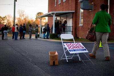 A woman passes a placard for Democratic Senatorial candidate Doug Jones as she walks over to get in the long line to vote at Beulah Baptist Church polling station in Montgomery, Alabama, on December 12, 2017.
The state of Alabama holds a closely-watched special election for US Senate featuring Republican candidate Roy Moore, who is endorsed by President Donald Trump despite being accused of molesting teenaged girls. / AFP PHOTO / JIM WATSON