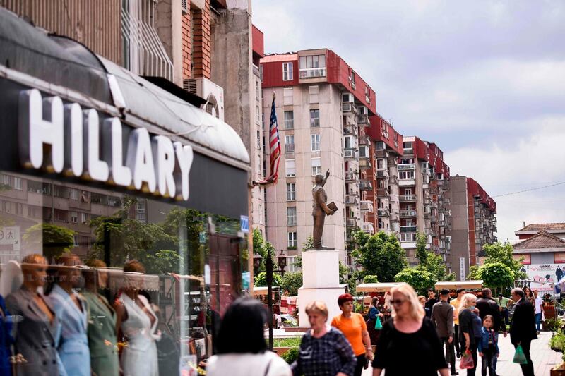 Pedestrians walk past a clothing store named after Hillary Clinton next to the statue of former US President Bill Clinton in Pristina on June 23. Armend Nimani / AFP