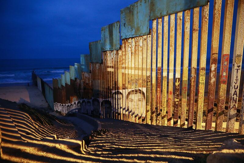 Images of those who perished attempting to migrate from Mexico into the United States line the Mexico side of the US-Mexico border fence in Tijuana, Mexico. Mario Tama / Getty Images