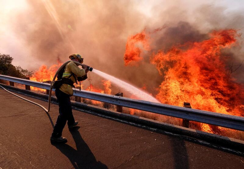 A firefighter battles a fire along the Ronald Reagan Freeway in Simi Valley, California. AP Photo