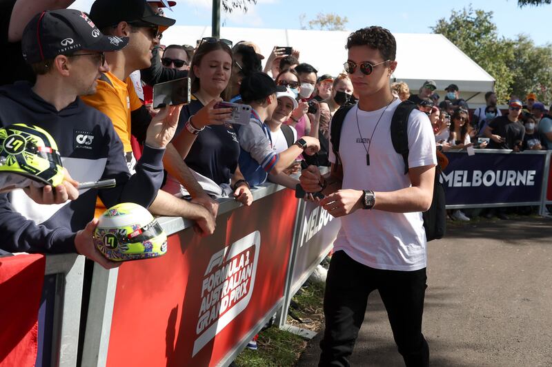 Mclaren driver Lando Norris signs autographs as he arrives at the track. AP