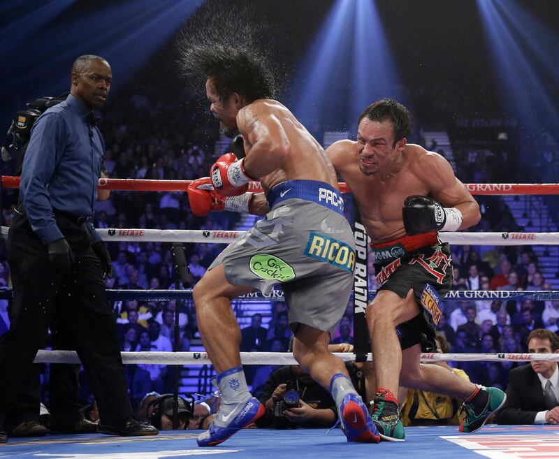 Juan Manuel Marquez, from Mexico, right, connects against Manny Pacquiao, from the Philippines, as referee Kenny Bayless looks on at left, during their WBO world welterweight  fight Saturday, Dec. 8, 2012, in Las Vegas. Marquez won the fight by a knockout. (AP Photo/Julie Jacobson) *** Local Caption ***  Pacquiao Marquez Boxing.JPEG-0dfe2.jpg
