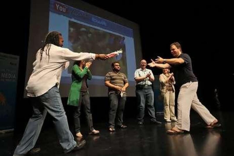 David Crane, left, and Ernesto Verdugo, right, hand out a prize of restaurant vouchers during a game of "The Price Is Right" at YouLearnTwitFace, an online marketing conference at the Dubai Community Theatre and Arts Centre in the Mall of the Emirates last weekend.