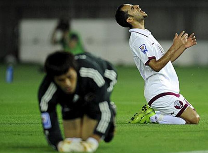 Qatar's midfielder Mohammed Abdulraab Alyazidi, right, reacts after missing the chance to score as Japan's goalkeeper Seigo Narazaki lies on the grass.