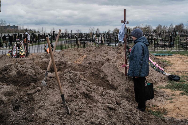 Nadia looks at her husband's coffin at a cemetery in Bucha. He was killed during the war. AFP