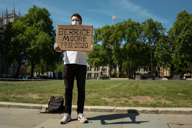 Ellis Tustin, grandson of Berrice Moore, holds up his grandfather's name as he stages a personal protest to Prime Minister Boris Johnson outside the Houses of Parliament on May 20. Getty Images