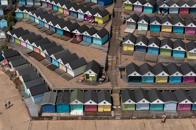 A man sunbathes in front of a row of beach huts in Walton-on-the-Naze amid temperatures of 30°C in parts of Britain. Getty Images