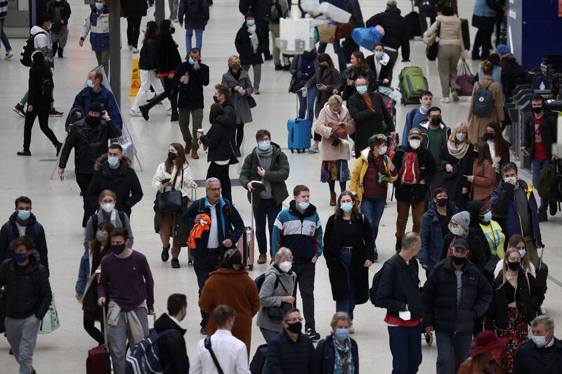 People wearing protective masks walk through Waterloo train station in London. Reuters