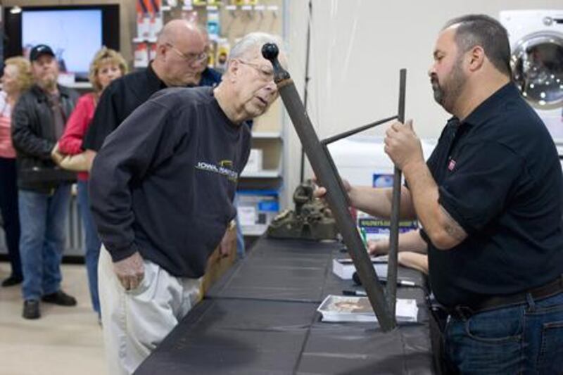 Bob Soesbe,  left, looks on as Frank Fritz, a treasure hunter from the TV show American Pickers, examines an old siphon, which Soesbe brought to the Craftsman Finding America’s Treasures event at the Sears Hometown Store in Clinton, Iowa in May last year.