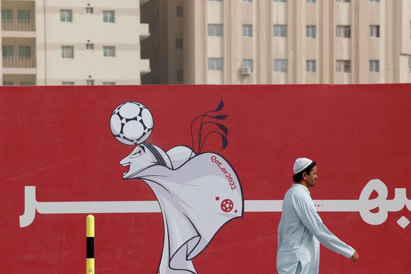 A man walks past a poster of the Qatar 2022 mascot La'eeb in Doha. AFP