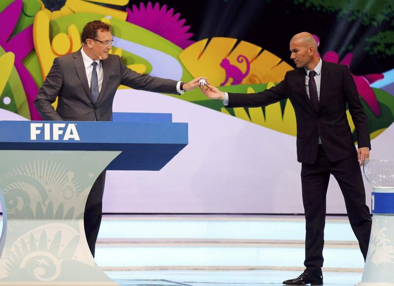 Zinedine Zidane, right, hands a ball that he had drawn from a pot to Jerome Valcke, the Fifa secretary general, during the draw for the 2014 World Cup at the Costa do Sauipe resort in Sao Joao da Mata yesterday. The 2014 World Cup finals will be held in Brazil from June 12 to July 13. Sergio Moraes / Reuters