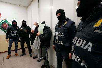 Iraqi suspects Alaa Qasim Rahima, third left and Omar Qasim Rahima, centre, conceal their faces after their arrest by Italian Finance Police, at the Venice barrack, northern Italy, Wednesday, Jan.  19, 2022. (AP Photo / Luca Bruno)