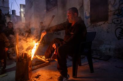 A man tends to a fire outside of his damaged home in Jenin, after raids by the Israeli military. Getty Images
