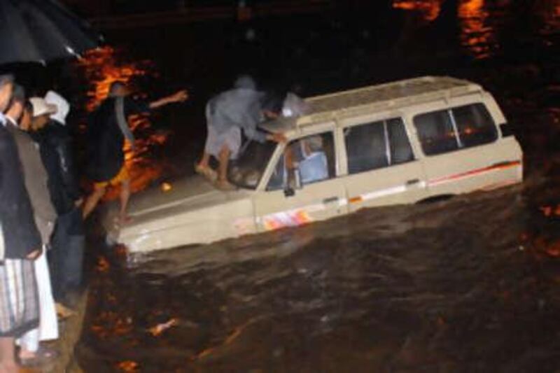 Yemenis ready to rescue a foreign tourist in a vehicle stranded in flood waters in the old sector of the Yemeni capital Sanaa.
