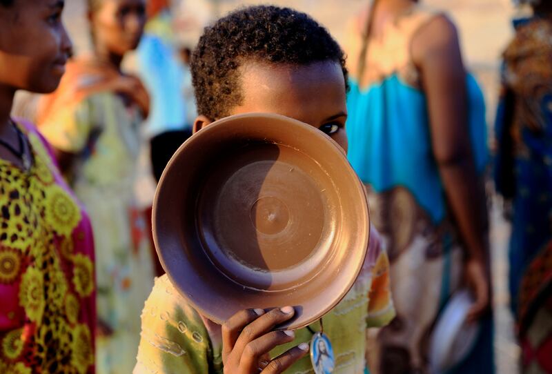 An Ethiopian child who fled war in Tigray region, carries his plate as he queues for wet food ration at the Um-Rakoba camp, on the Sudan-Ethiopia border in Al-Qadarif state, Sudan November 19, 2020. REUTERS/Mohamed Nureldin Abdallah     TPX IMAGES OF THE DAY