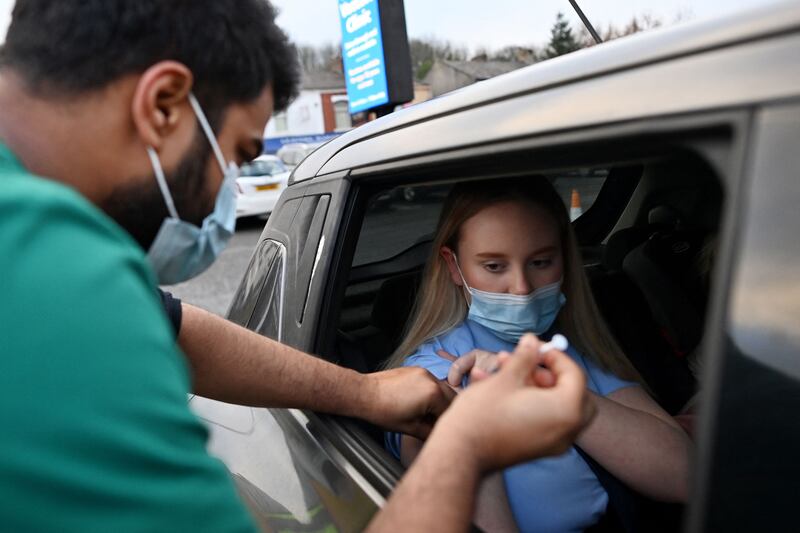 A health worker inoculates a woman at a drive-through NHS vaccination centre outside Ewood Park stadium in Blackburn. AFP