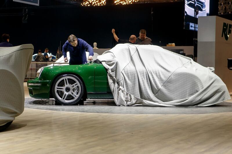 A representative of the RUF booth cleans a car on the Porsche restoration company's stand. Keystone via AP