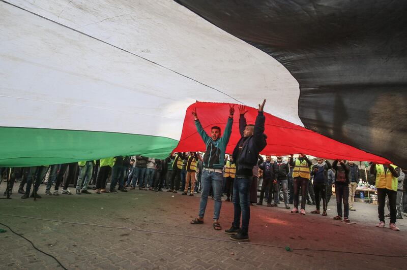 Protesters stand under a giant Palestinian flag during a demonstration against US President Donald Trump's Middle East peace proposal in Khan Yunis in the southern Gaza Strip. AFP