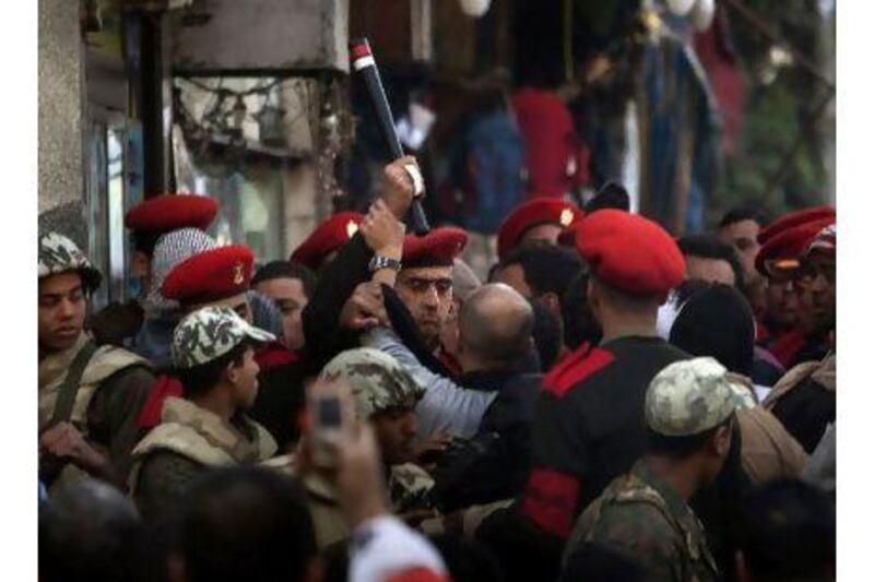 Military police officers scuffle with protesters as they try to clear Tahrir Square in Cairo yesterday.