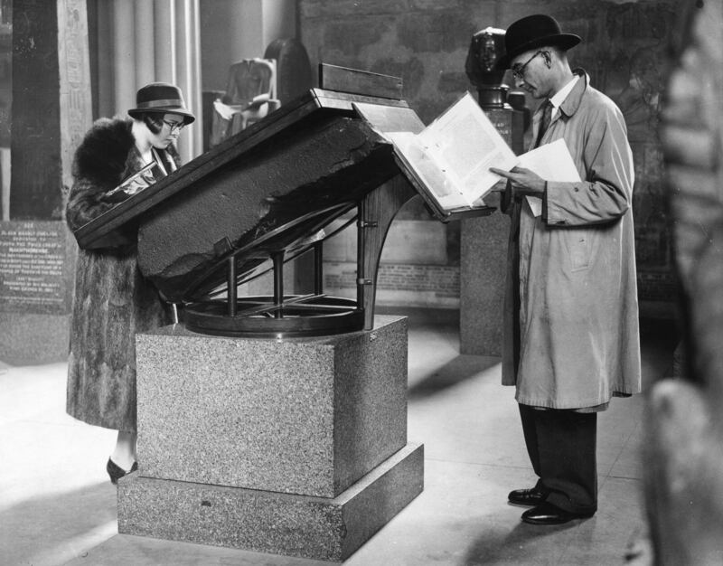 Visitors reading information concerning the Rosetta Stone, from the top of the stone itself, in the Egyptian Gallery in 1932