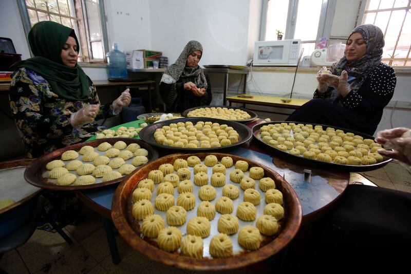 Palestinian women make traditional cookies filled with dates or nuts in preparation for the Eid al-Adha celebrations, on August 28, 2017, in the West Bank town of Hebron. / AFP PHOTO / HAZEM BADER