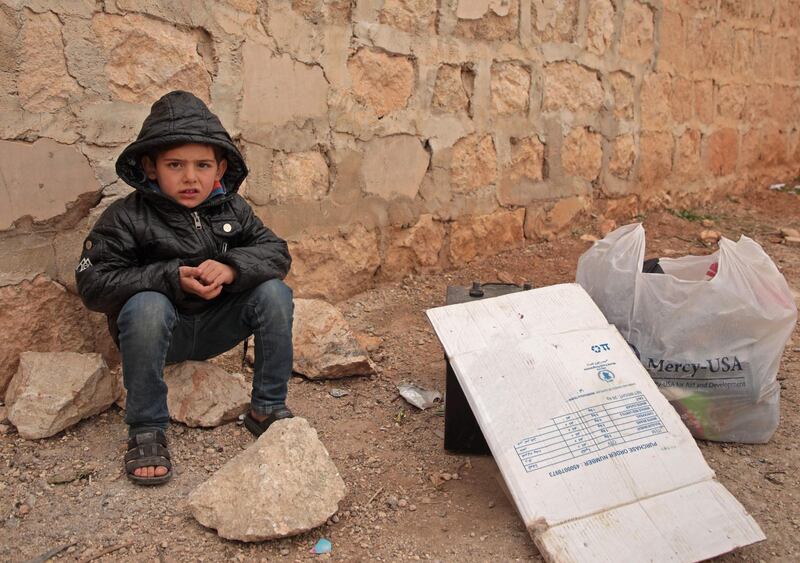 A displaced Syrian boy sits on the ground next to belongings in Khan al-Assal town in Syria's northwestern Aleppo province on January 16, 2020.  / AFP / Aaref WATAD
