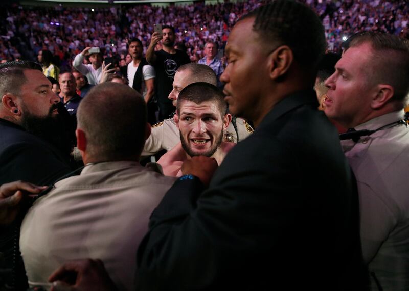 Khabib Nurmagomedov is held back outside of the cage. AP Photo