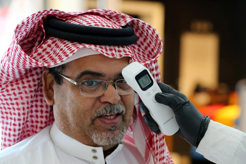 A security guard checks the temperature of a man at a shopping mall after the Saudi government eased a curfew and allowed stores to open, following the outbreak of the coronavirus disease (COVID-19), in Riyadh, Saudi Arabia May 2, 2020. REUTERS/Ahmed Yosri