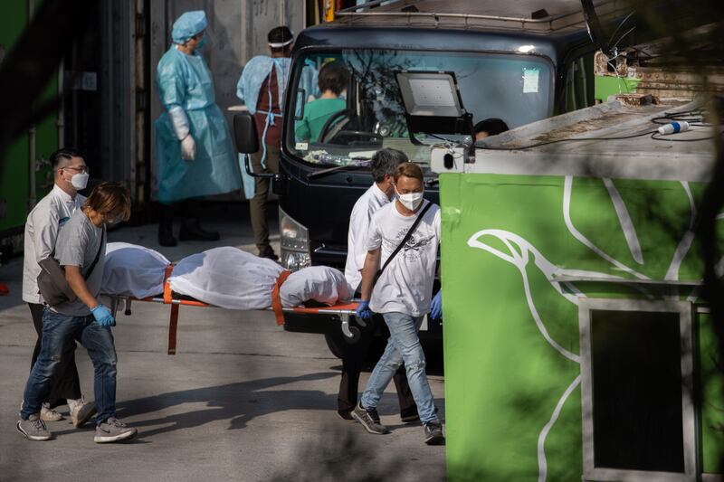 Workers move a body from a refrigerated shipping container into a hearse for cremation. Photo: EPA