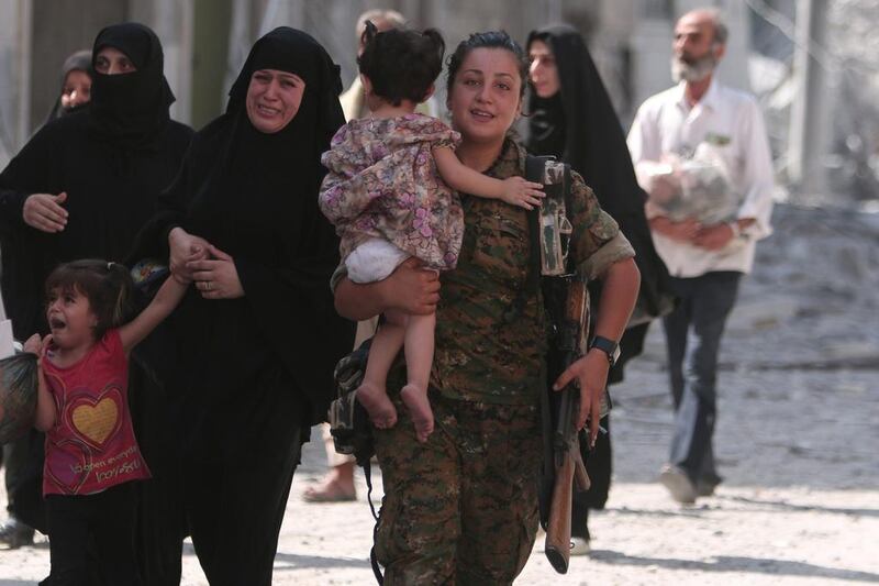 A Syria Democratic Forces fighter helps civilians who were evacuated by the SDF from an ISIL-controlled neighbourhood of Manbij, in Aleppo. Rodi Said / Reuters