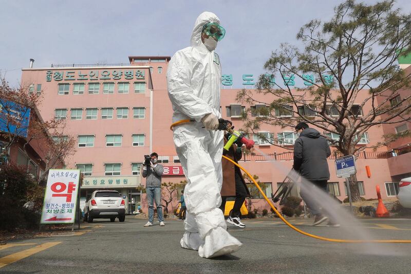 A worker wearing protective gear sprays disinfectant against the coronavirus in front of the Daenam Hospital in Cheongdo, South Korea. Lim Hwa-young/Yonhap via AP