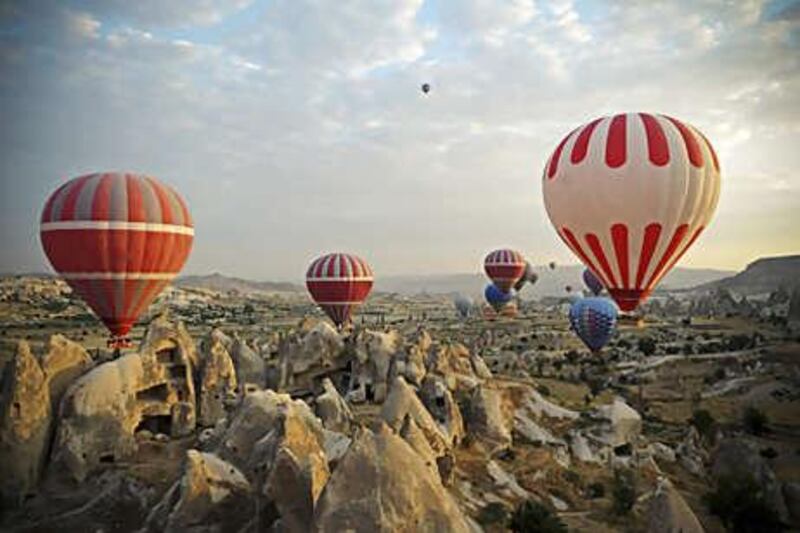 Tourists enjoy hot-air balloon rides over the spectacular soft rock formations near Goreme in Cappadocia. The rocks are volcanic deposits that have eroded over the centuries and were carved out to form vast underground cities.