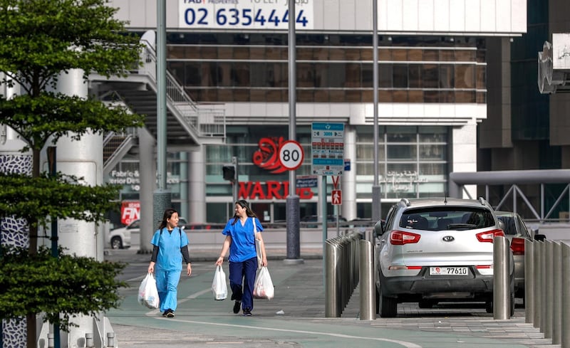 Abu Dhabi, United Arab Emirates, March 27, 2020.  Healthworkers with groceries on the nearly empty streets at downtown Abu Dhabi on the first day of the UAE cleaning campaign.  Emiratis and residents across the UAE must stay home this weekend while a nationwide cleaning and sterilisation drive is carried out.
 Victor Besa / The National