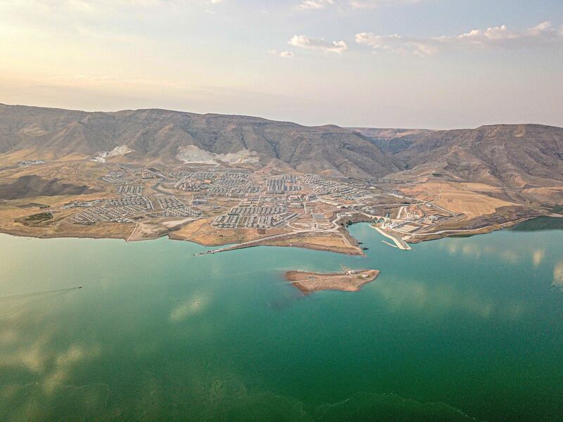 This picture taken on August 6, 2020, shows the Il?su Dam separating the  newly government built Hasankeyf town and the remains of the ancient town of the same name and its archaeological sites which were flooded as part of the Il?su Dam project located along the Tigris River in the Batman Province in southeastern Turkey. - Despite years of protests by residents and activists, the town on the banks of the Tigris River disappeared under water as part of a controversial dam project. To encourage tourism, swimming is allowed and people can enjoy a boat tours. (Photo by BULENT KILIC / AFP)