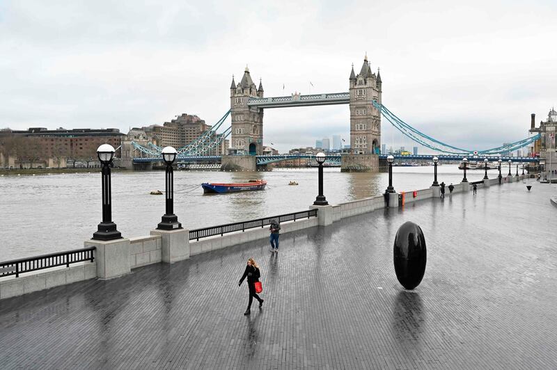 People walk along a very quiet bank of the River Thames in London. AFP