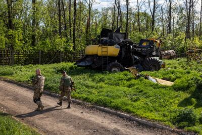 Ukrainian soldiers pass farm equipment destroyed by Russian tanks in Cherkska Lozova, Ukraine. Getty Images
