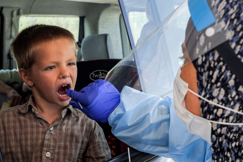 A medic performs a Covid-19 throat swab saliva test on a child. Menahem Kahana / AFP